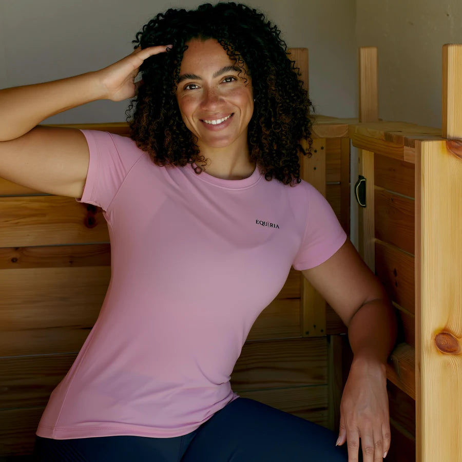 Amazzone con la maglia Equiria rosa accanto al baule della sella